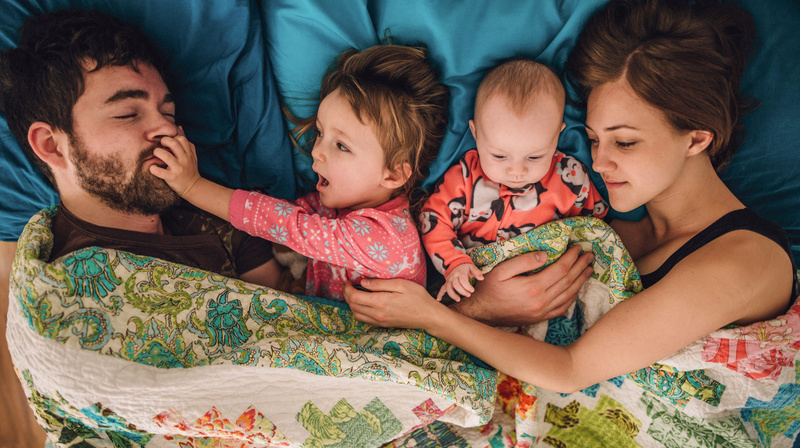 Family of four cuddling in bed 