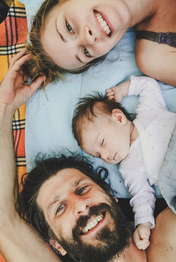 mom, dad and baby lying in bed together 