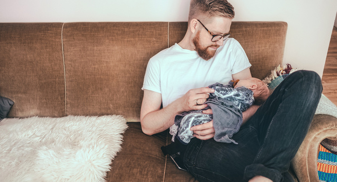 dad on the couch with sleeping baby on lap